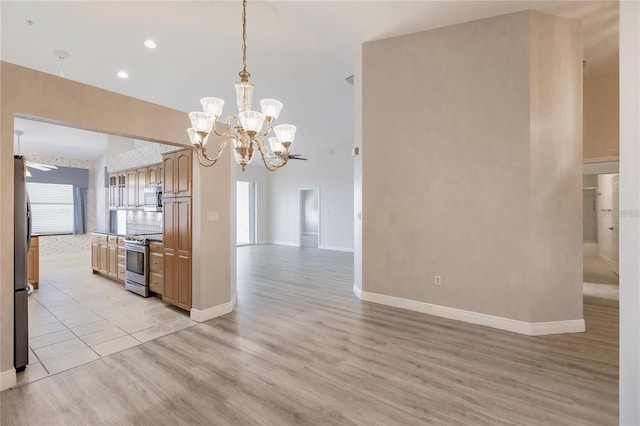 interior space with stainless steel appliances, open floor plan, baseboards, light wood-style floors, and pendant lighting