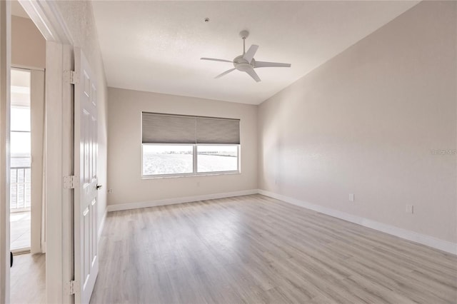 spare room featuring light wood finished floors, a ceiling fan, and baseboards