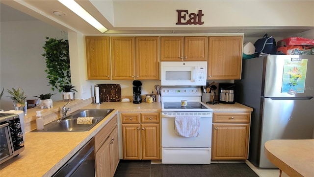 kitchen featuring light countertops, white appliances, and a sink