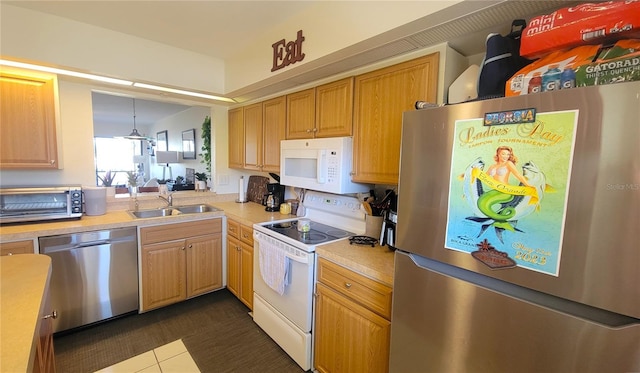 kitchen featuring stainless steel appliances, a toaster, a sink, light countertops, and dark tile patterned flooring