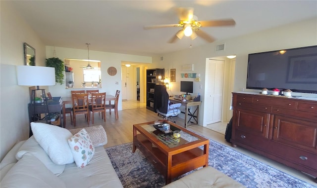 living area featuring light wood finished floors, visible vents, and ceiling fan
