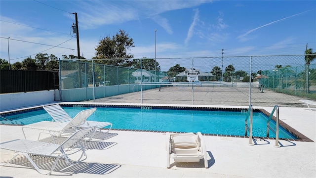 community pool with a patio area and fence
