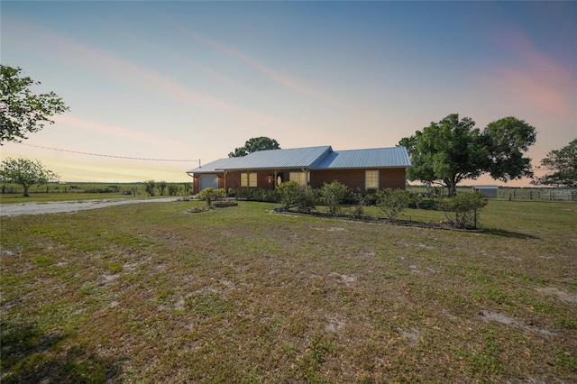view of front facade with an attached garage, metal roof, dirt driveway, and a front yard