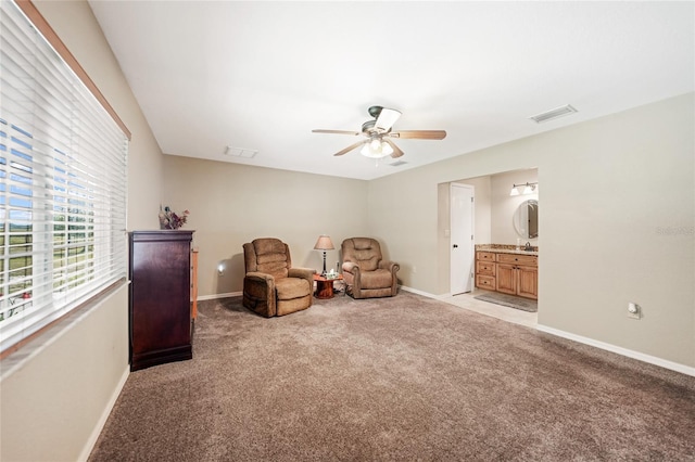 sitting room featuring ceiling fan, visible vents, baseboards, and light carpet