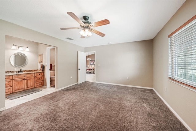 unfurnished bedroom with light colored carpet, a sink, visible vents, and ensuite bathroom
