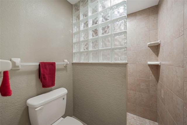 bathroom featuring toilet, a textured wall, and a walk in shower