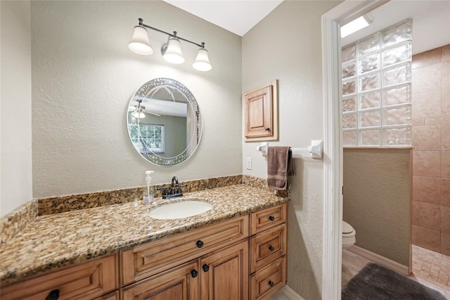 full bath with a ceiling fan, vanity, a walk in shower, and toilet