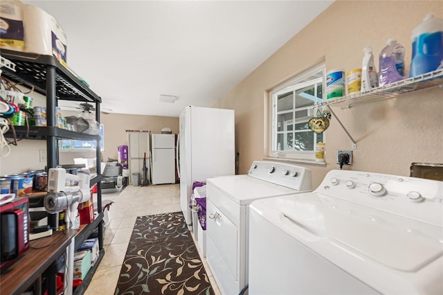 clothes washing area with light tile patterned floors, washer and dryer, and laundry area