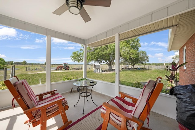 sunroom with a rural view, a ceiling fan, and a healthy amount of sunlight