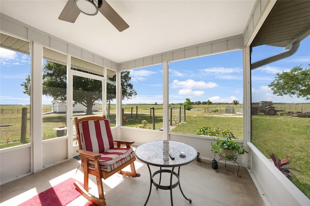 sunroom / solarium with a rural view, ceiling fan, and a healthy amount of sunlight