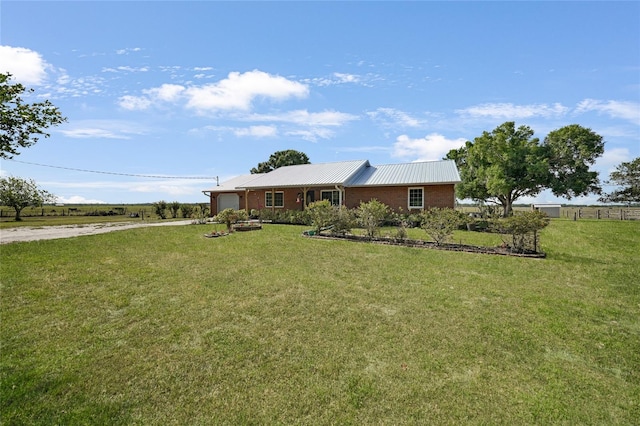 view of front of property featuring an attached garage, driveway, a front lawn, and metal roof