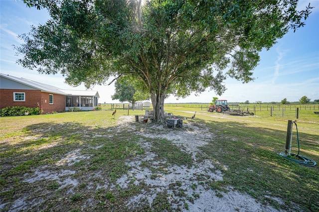 view of yard featuring a sunroom, fence, and a rural view