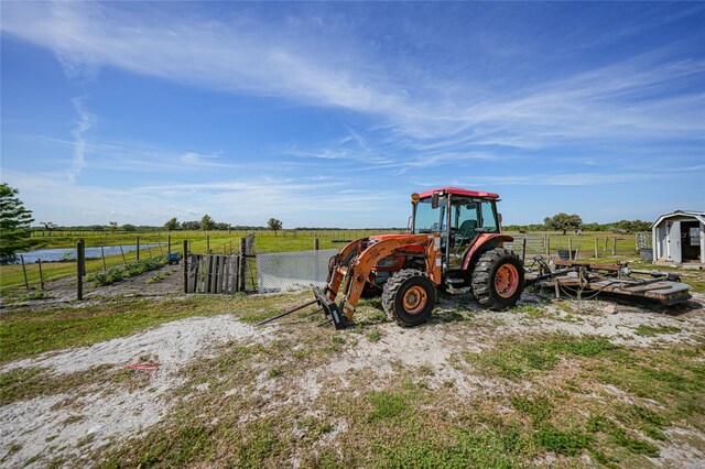 view of jungle gym featuring a rural view, a storage unit, an outbuilding, and fence