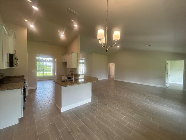 23245 Jules Ave, Port Charlotte, FL 33980 - kitchen with appliances with stainless steel finishes, vaulted ceiling, open floor plan, white cabinets, and dark stone countertops