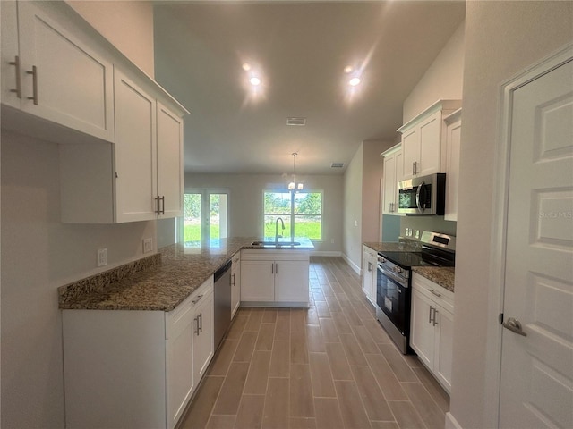 23245 Jules Ave, Port Charlotte, FL 33980 - kitchen featuring appliances with stainless steel finishes, a peninsula, white cabinets, dark stone counters, and recessed lighting