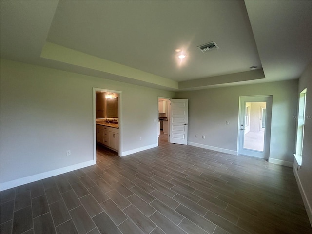 23245 Jules Ave, Port Charlotte, FL 33980 - unfurnished bedroom with a tray ceiling, recessed lighting, ensuite bath, and dark wood-style flooring