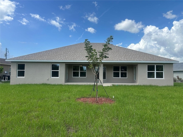 23245 Jules Ave, Port Charlotte, FL 33980 - back of house featuring stucco siding, a shingled roof, and a lawn