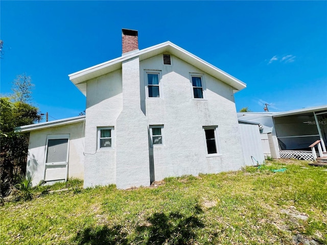 view of property exterior with a chimney, a yard, and stucco siding