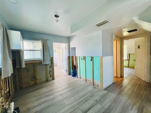 unfurnished room with wood finished floors, visible vents, and a wealth of natural light