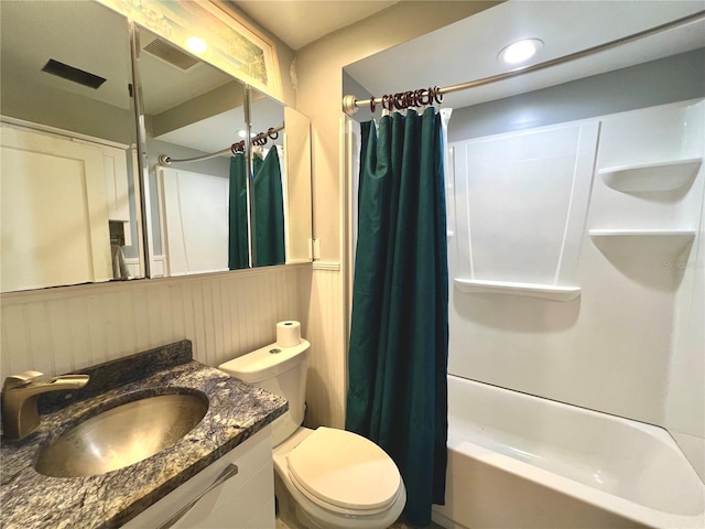 full bathroom featuring a wainscoted wall, visible vents, toilet, vanity, and shower / tub combo