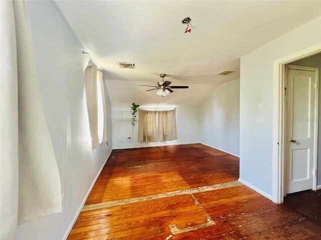 unfurnished room featuring hardwood / wood-style floors, ceiling fan, baseboards, lofted ceiling, and visible vents