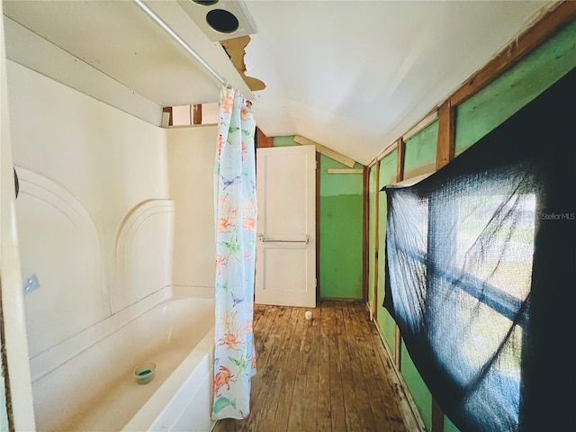 full bath with shower / tub combo, lofted ceiling, and wood finished floors