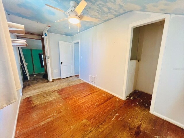unfurnished bedroom with wood-type flooring, lofted ceiling, visible vents, and baseboards