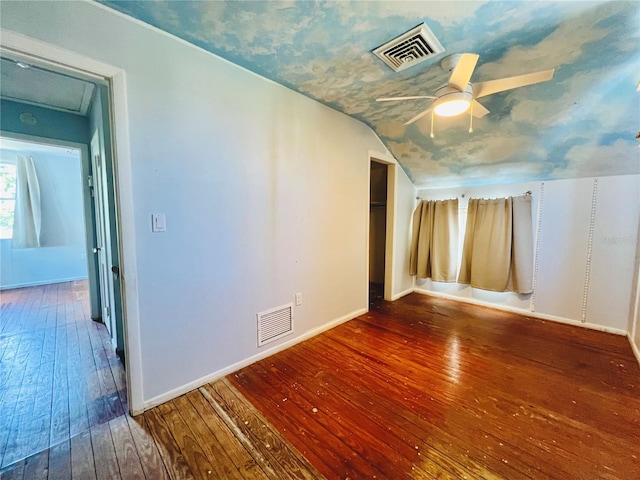 empty room with baseboards, vaulted ceiling, visible vents, and hardwood / wood-style flooring