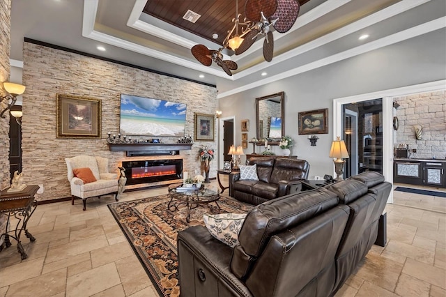 3866 Turtle Dove Blvd, Punta Gorda, FL 33950 - living room featuring a raised ceiling, a glass covered fireplace, stone tile flooring, ornamental molding, and recessed lighting
