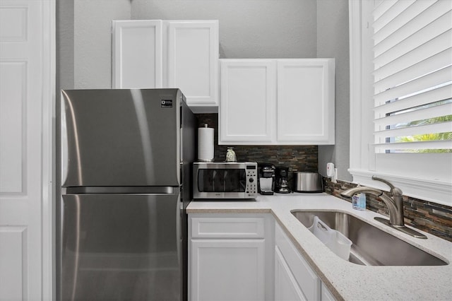 3866 Turtle Dove Blvd, Punta Gorda, FL 33950 - kitchen featuring appliances with stainless steel finishes, a sink, white cabinets, tasteful backsplash, and light stone countertops