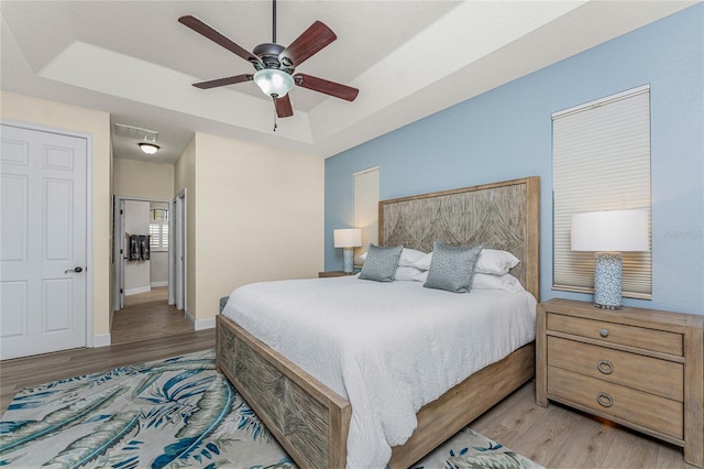 4015 La Costa Island Ct, Punta Gorda, FL 33950 - bedroom with wood finished floors, a raised ceiling, attic access, baseboards, and ceiling fan
