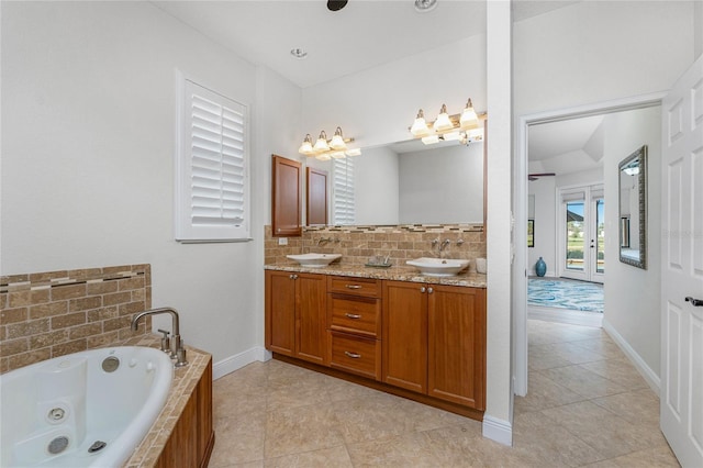 4015 La Costa Island Ct, Punta Gorda, FL 33950 - bathroom featuring double vanity, tile patterned floors, a tub with jets, backsplash, and baseboards