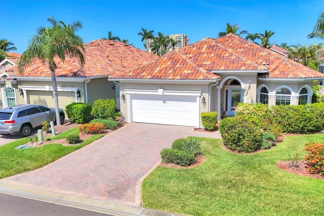 303 11th Ave E, Palmetto, FL 34221 - view of front of home featuring stucco siding, an attached garage, a tiled roof, a front yard, and decorative driveway