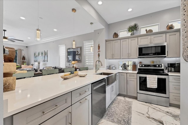 303 11th Ave E, Palmetto, FL 34221 - kitchen with appliances with stainless steel finishes, a sink, light marble finish floors, gray cabinets, and a peninsula