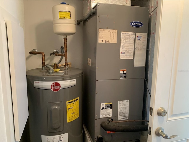 utility room featuring heating unit and electric water heater