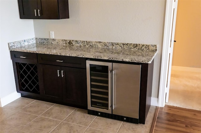 bar featuring wine cooler, baseboards, and light tile patterned flooring