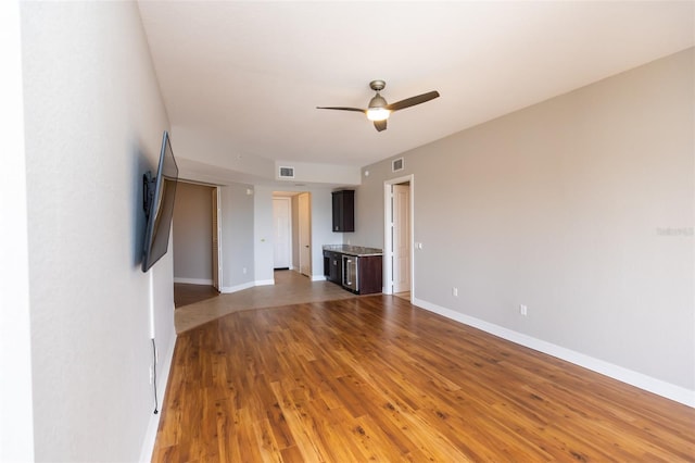 unfurnished living room featuring baseboards, a ceiling fan, visible vents, and wood finished floors