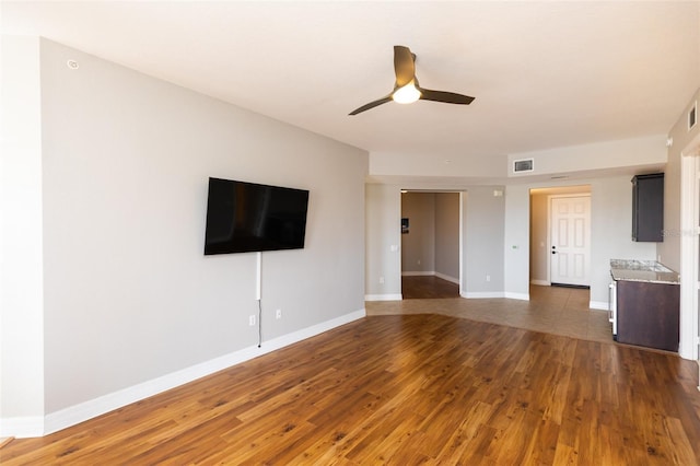 unfurnished living room with baseboards, visible vents, wood finished floors, and a ceiling fan