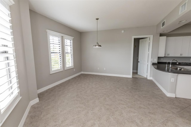 interior space featuring hanging light fixtures, dark countertops, visible vents, and a sink