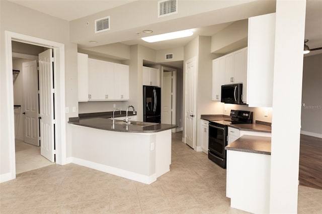 kitchen with a peninsula, a sink, dark countertops, visible vents, and black appliances