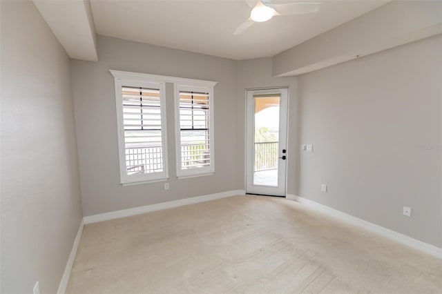 empty room with light colored carpet, baseboards, and ceiling fan