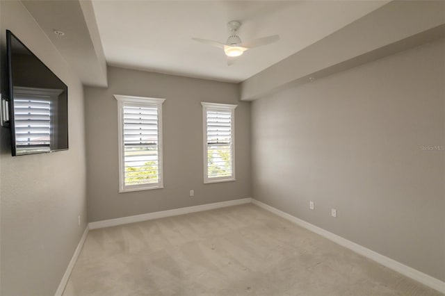 spare room with baseboards, a ceiling fan, and light colored carpet