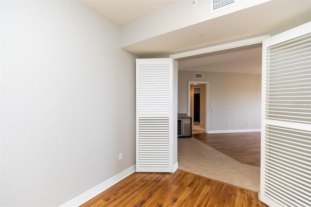 spare room featuring baseboards, dark wood-style floors, and visible vents