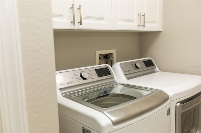 laundry area with cabinet space, independent washer and dryer, and a textured wall