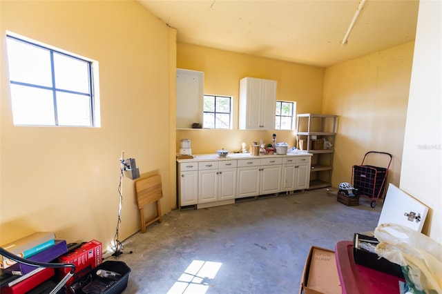 kitchen with white cabinets, light countertops, and concrete flooring