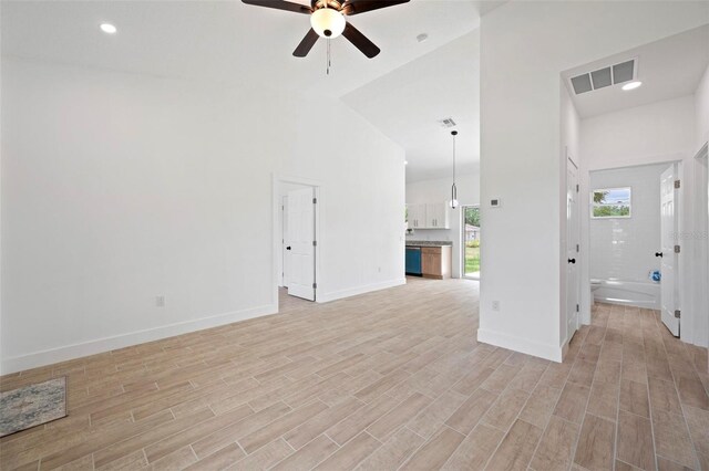 21480 Eldred Ave, Port Charlotte, FL 33952 - unfurnished living room featuring a ceiling fan, light wood finished floors, baseboards, and a towering ceiling