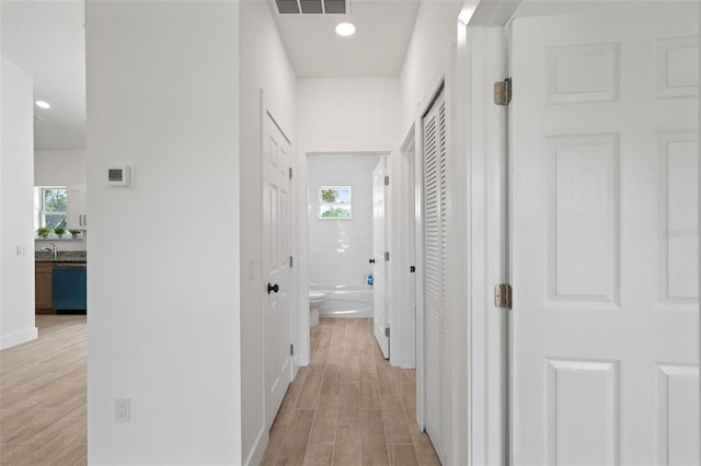 21480 Eldred Ave, Port Charlotte, FL 33952 - hallway featuring healthy amount of natural light, light wood-type flooring, recessed lighting, and a sink
