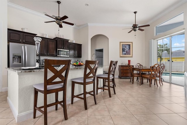 18652 Ohara Dr, Port Charlotte, FL 33948 - kitchen with stainless steel appliances, arched walkways, light tile patterned flooring, ceiling fan, and crown molding