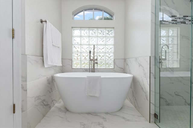 18652 Ohara Dr, Port Charlotte, FL 33948 - bathroom featuring a soaking tub, tile walls, wainscoting, marble finish floor, and a shower stall