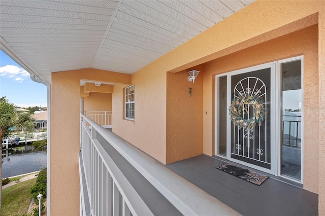 doorway to property featuring a water view, stucco siding, and a balcony